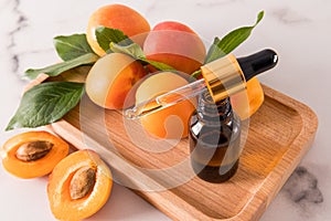 an open bottle with a dropper of cosmetic organic oil apricot on a tray wooden of fruity for face and body skin care