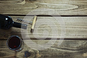 Open bottle of red wine with a glass, corkscrew on a wooden board. Copy space and top view.