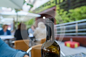 Open bottle of red wine at an outdoor restaurant with patrons