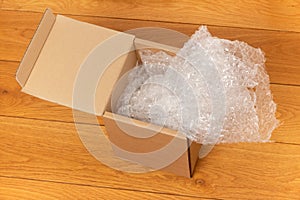 Open box with bubble wrap on a wooden floor