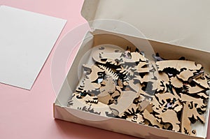 Open-box with a wooden puzzle on a pink background. A complex puzzle of highly accurate shapes and articulations photo