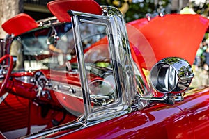 Open bright red vintage retro convertible car with chrome details and moldings exhibited at a provincial town street exhibition