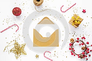 Open brown envelope with blank white card and Christmas decorations, candy canes and gift box on white background. Top