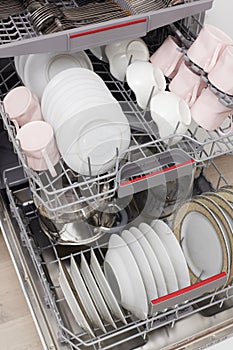 Open built-in dishwasher with clean dishes in white kitchen