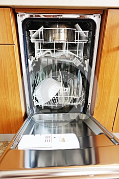 Open built-in dishwasher machine with clean dishes inside photo