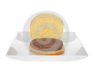 Open bun on square white plate with plain hamburger patty