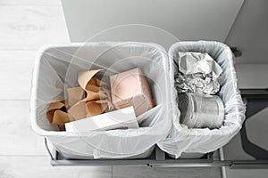 Open cabinet with full trash bins for separate waste collection in kitchen, above view