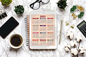 Open Calendar 2021 on tablet, glasses, cup of coffee, pen, smartphone, succulents on marble table