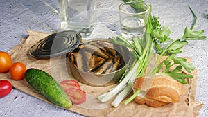 Open can of sprats on paper on a cement background