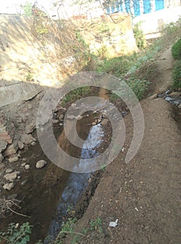 Open canal industrial wastage drainage line aside of small road for passing