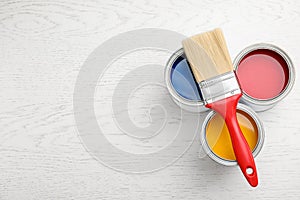 Open cans with paint and brush on white wooden table. Space for text