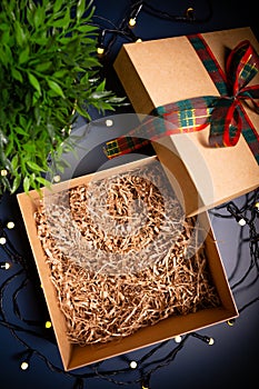 Open carton present box with ribbon on blue background surrounded by decorative lights.