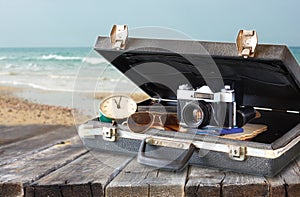 Open case with old camera sunglasses and clock