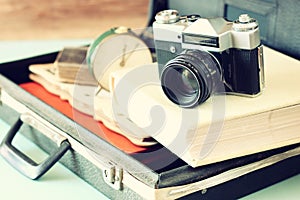 Open case with old camera sunglasses and clock in front of seascape
