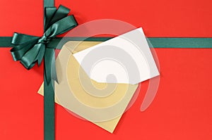 Open Christmas or birthday card, green gift ribbon bow on plain red paper background
