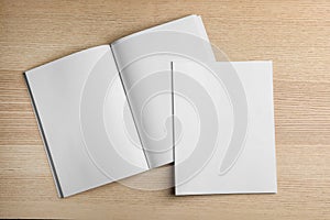 Open and closed blank brochures on wooden background, top view.