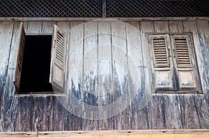 Open and closed wooden windows on a black wall of traditional house in Asia