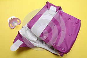 Open Cloth Diaper with Dummy on Yellow Background photo