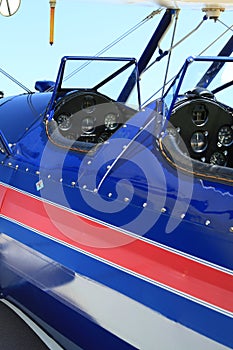 Open cockpit red white and blue aircraft airplane at airport close up featuring pilots and passenger or copilots seats instruments