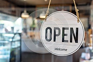 Open. coffee cafe shop text on vintage sign board hanging on glass door in modern cafe shop reopen after coronavirus quarantine is