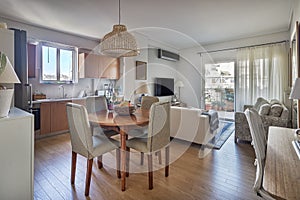 Open-concept of a kitchen, dining wooden table and living room.