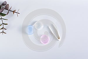 An open container with contact lenses and tweezers on a blue background. Top view