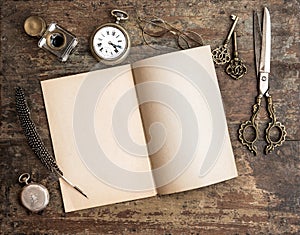 Open diary book and antique writing tools on wooden background