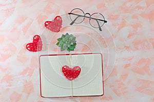 Open diary, hearts, glasses and cactus on pink background