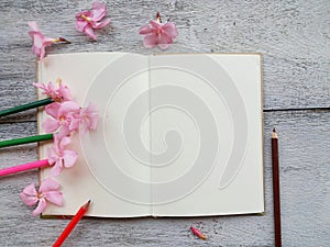 open diary and pencil pink flower on wood background