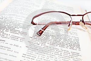 Open dictionary book and glass