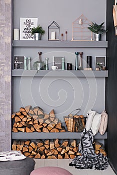 Open dining room interior with firewood, shelves on the grey wall and wooden log wall decoration for warm cozy