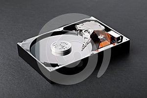 Open disassembled hard disk on black plastic background