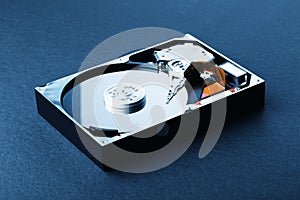 Open disassembled hard disk on black plastic background. Blue Toned Image