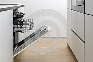 Open dishwasher with basket and clean tableware inside