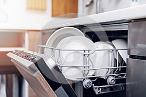 Open dishwasher with clean dishes at home kitchen