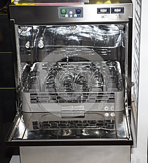 Open dishwasher with clean glass, cups, plates and dishes