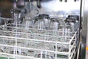 Open dishwasher with clean glass, cups, plates and dishes, selective focus