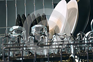 Open dishwasher with clean plates and glasses