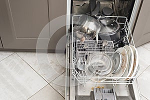 Open dishwasher with dirty dishes, plates, spoons, forks, cutlery, dishwasher tray