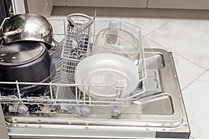 Open dishwasher with dirty dishes, plates, spoons, forks, cutlery, dishwasher tray