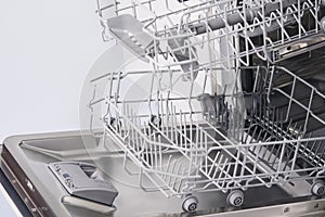 Open dishwasher door and empty extended grates for dirty dishes photo