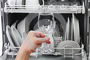 Open dishwasher, man hand taking out clean wine glass, after washing