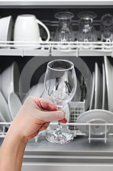 Open dishwasher, man hand taking out clean wine glass, after washing