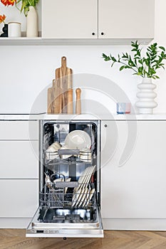 Open dishwasher in modern kitchen interior design in white tones