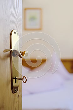 Open door with key in the keyhole in the hotel room on the bed, heart-shaped blanket, two pillows, white cotton bed linen, the