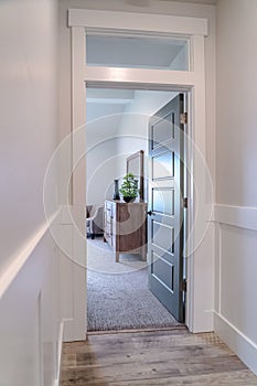 Open door leading to a bedroom with cabinet mirror carpet floor and armchair