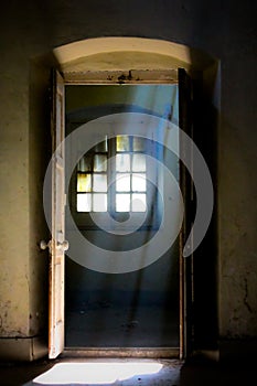 An open door of an old building through which sun rays pass.