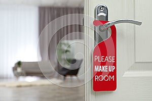 Open door with sign PLEASE MAKE UP ROOM on handle at hotel