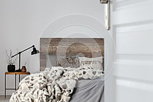 Open door to grey elegant bedroom interior with rustic design, copy space on empty wall
