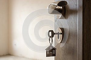 Open door to a new home. Door handle with key and home shaped keychain. Mortgage, investment, real estate, property and new home